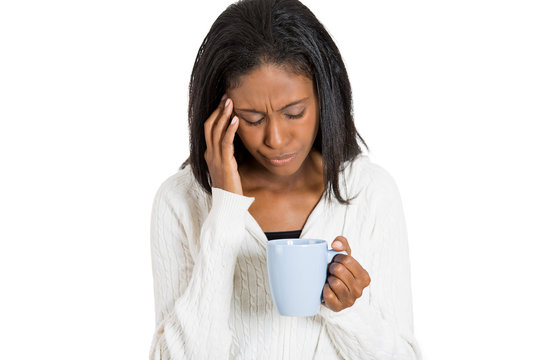 Tired sad woman looking at cup of coffee white background 