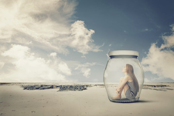 young woman sitting in jar in desert. Loneliness outlier concept