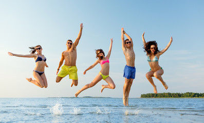 smiling friends in sunglasses on summer beach