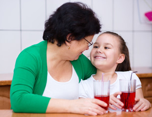 Grandmother with her grandchildren drink juice
