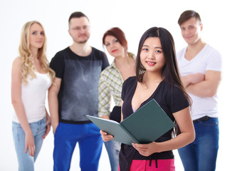 young smiling asian with a book on a background of a group of yo