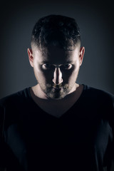 Man posing with angry face and dark background with hard lightin