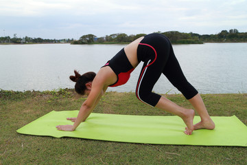 Fototapeta premium Young woman doing yoga exercise in the park