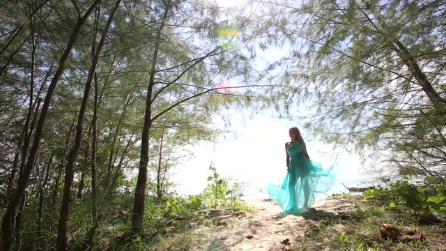 asian girl gorgeous blue dress blows under wind near small palms
