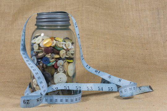 Jar of buttons draped with seamstress measuring tape