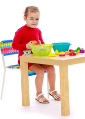 Smiling child sitting at the table and play.