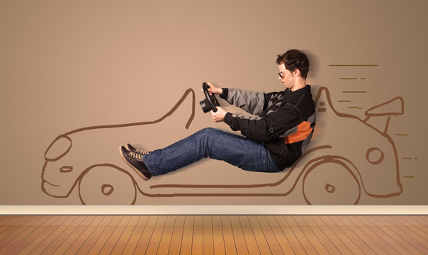 Happy man driving an hand drawn car on the wall