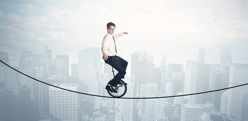 Brave guy riding a monocycle on a rope above cityscape © ra2 studio
