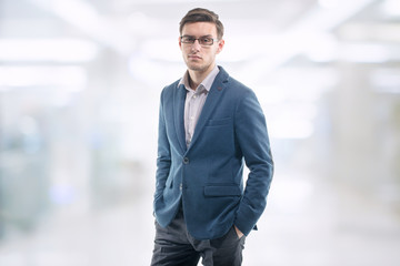 Fototapeta premium Young handsome guy wearing glasses in the office and standing