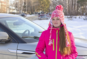 Fototapeta na wymiar Рortrait of a girl with a red cap with a pompom near the car