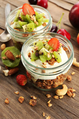 Healthy layered dessert with muesli and fruits on table