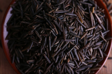 Black rice on plate on wooden background