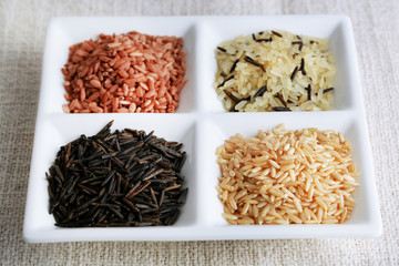 Fototapeta na wymiar Different types of rice on plate on fabric background