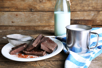 Metal mug and glass bottle of milk with chocolate chunks and