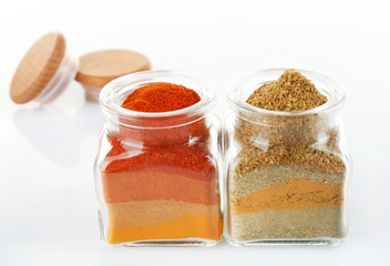 Different kinds of spices in glass bottles isolated on white