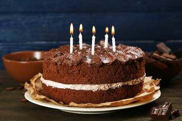 Delicious chocolate cake on table on blue background