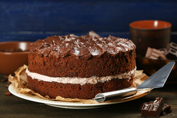 Delicious chocolate cake on table on blue background