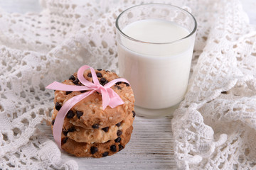 Tasty cookies and glass of milk on color wooden background
