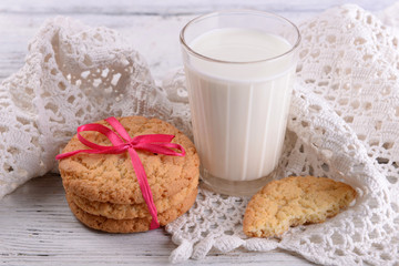 Tasty cookies and glass of milk on color wooden background