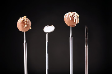 Dentist tools with sweets on dark background