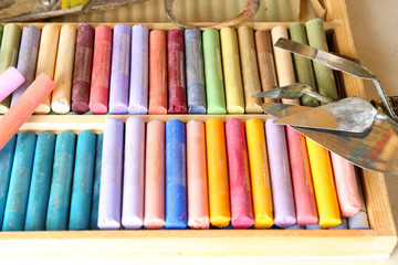 Colorful chalk pastels in box with palette knifes close up