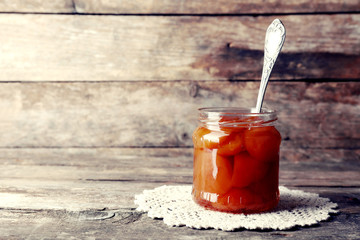 Jar of tasty jam on wooden background