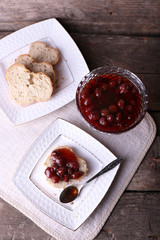 Fresh bread with jam on plate on wooden background