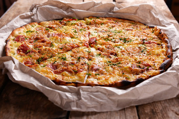 Tasty pizza on paper on wooden background