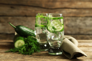 Glasses with fresh organic cucumber water on wooden table