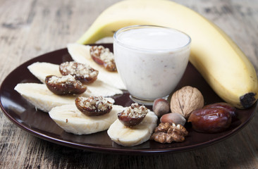 Bananas with dates , nuts and a cup of yogurt.