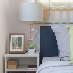 modern white lamp on table with pillows on bed
