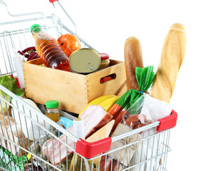 Shopping cart full with various groceries isolated on white