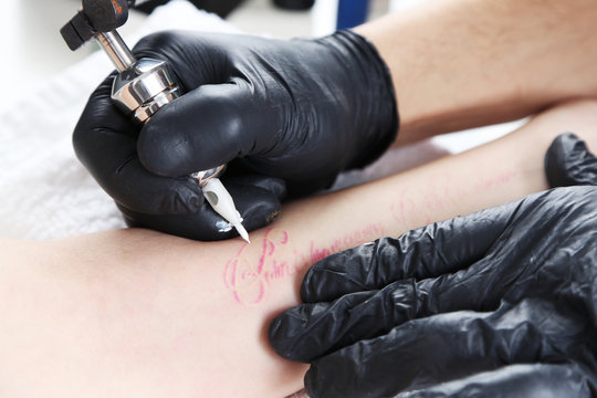 Tattooer showing process of making tattoo, close up