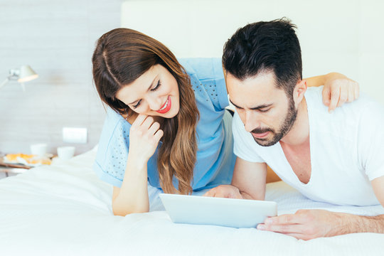 Young Couple with Digital Tablet on Bed.
