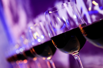 Nightclub glasses with red wine lit by festive lights