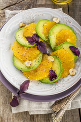 Appetizer of avocado, orange with purple basil and hazelnuts