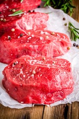 raw steaks with rosemary, salt and pepper