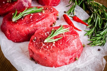 two raw steaks with rosemary, garlic, salt and pepper