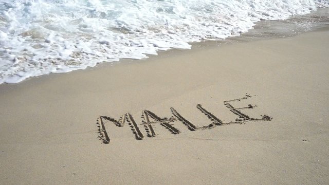 Wort MALLE am Strand wird von Wellen weggesp&uuml;lt