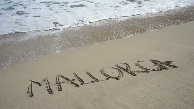 Wort MALLORCA am Sandstrand wird von Wellen weggesp&uuml;lt