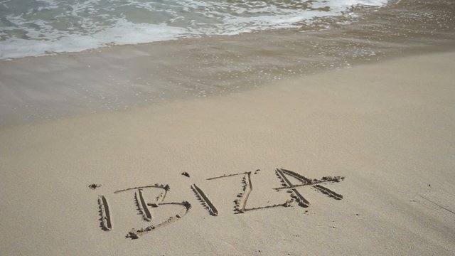 Wort IBIZA am Sandstrand wird von Wellen weggespült
