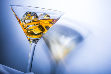 Orange liqueur into a martini glass. Multicolored reflections.