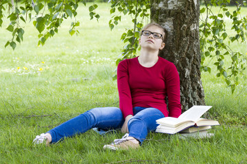 Naklejka na ściany i meble Young girl reading book in park in spring day