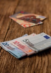 Euro bills on wooden board with credit cards in background