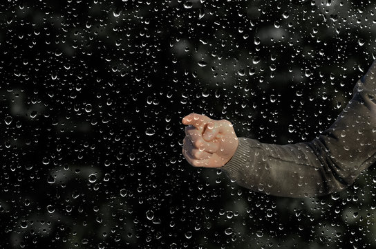 hand behind a wet window