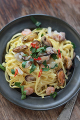 Fettuccine with seafood, chili and parsley on a tin plate.