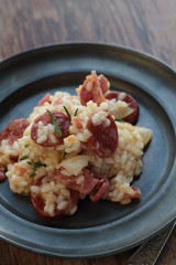 Risotto with sausage, cured ham and rosemary on a tin plate.