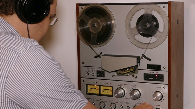 man with headphones working with reel tape recorder