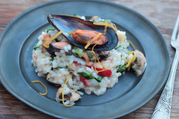 Risotto with seafood, chili and parsley on a tin plate.