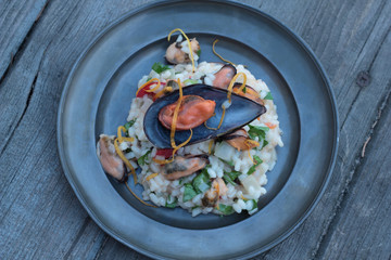 Risotto with seafood, chili and parsley on a tin plate.